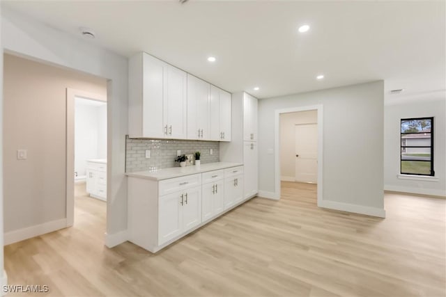 kitchen with decorative backsplash, white cabinets, and light wood-type flooring