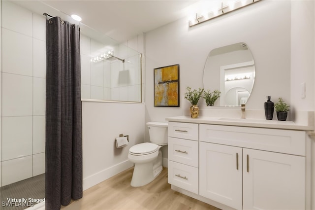 bathroom featuring vanity, wood-type flooring, toilet, and tiled shower