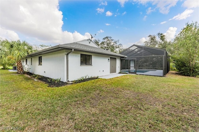 back of property featuring a patio area, a lawn, and glass enclosure