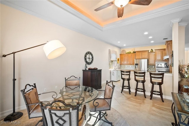 tiled dining space featuring ceiling fan, ornamental molding, and a tray ceiling