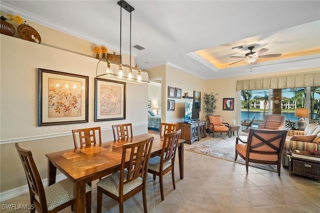 tiled dining space with crown molding, a raised ceiling, and ceiling fan