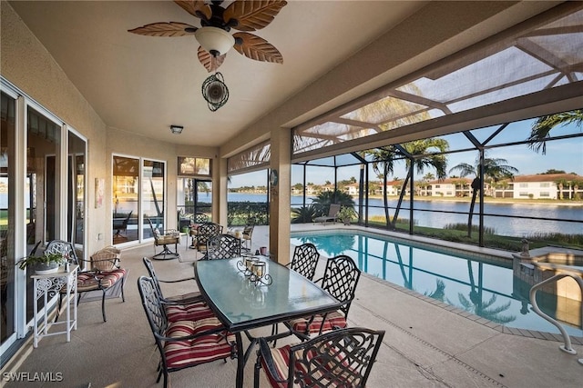 view of swimming pool featuring a lanai, a patio, ceiling fan, and a water view