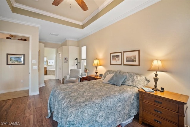 bedroom with dark hardwood / wood-style flooring, connected bathroom, crown molding, and a raised ceiling