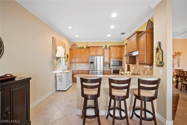 kitchen featuring tasteful backsplash, appliances with stainless steel finishes, kitchen peninsula, and a breakfast bar area