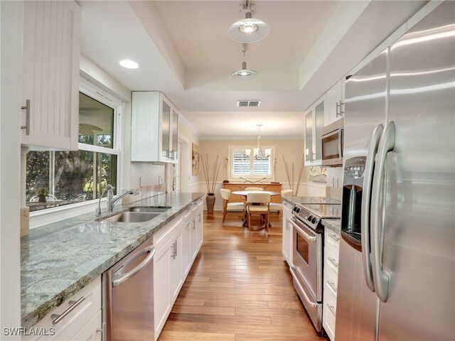 kitchen featuring white cabinetry, sink, stainless steel appliances, and hanging light fixtures