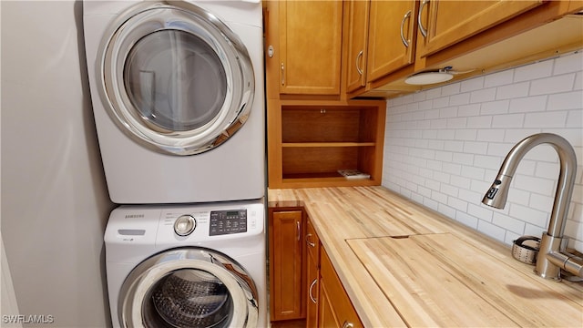 clothes washing area with cabinets and stacked washer and clothes dryer