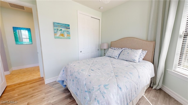 bedroom with light hardwood / wood-style floors and a closet