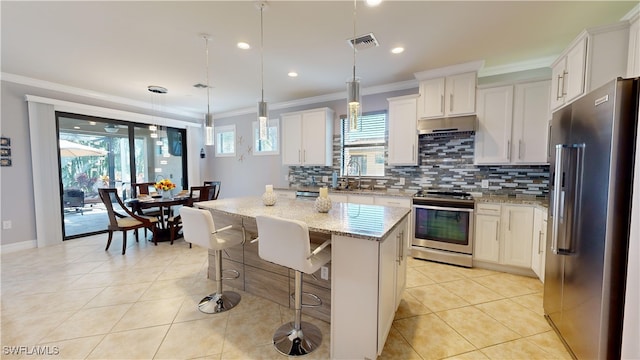 kitchen with appliances with stainless steel finishes, white cabinets, hanging light fixtures, a center island, and light stone countertops