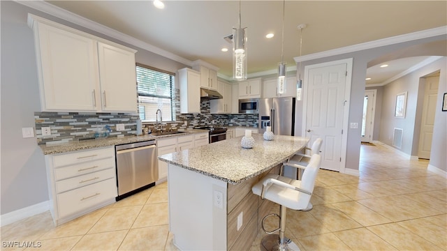 kitchen with sink, light tile patterned floors, a kitchen island, pendant lighting, and stainless steel appliances