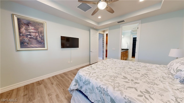 bedroom featuring ceiling fan, light hardwood / wood-style floors, and a tray ceiling