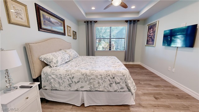 bedroom featuring a tray ceiling, light hardwood / wood-style floors, and ceiling fan