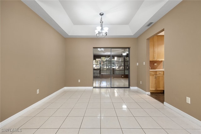 unfurnished dining area featuring an inviting chandelier, a tray ceiling, and light tile patterned floors