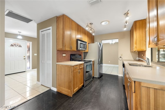 kitchen featuring appliances with stainless steel finishes, sink, light tile patterned floors, and decorative backsplash