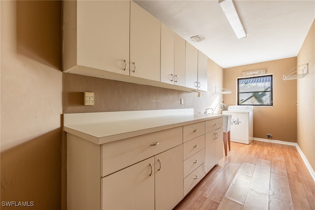 laundry room with cabinets, light hardwood / wood-style floors, and washer / clothes dryer