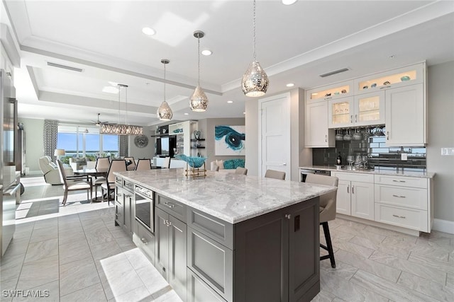 kitchen featuring white cabinetry, pendant lighting, a raised ceiling, and a kitchen island