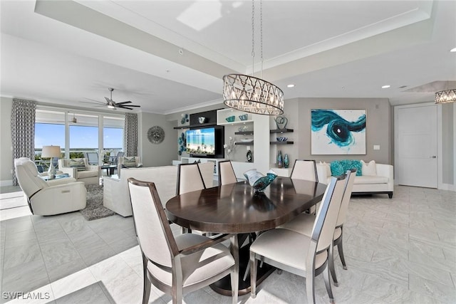 dining area featuring crown molding, a tray ceiling, and ceiling fan with notable chandelier