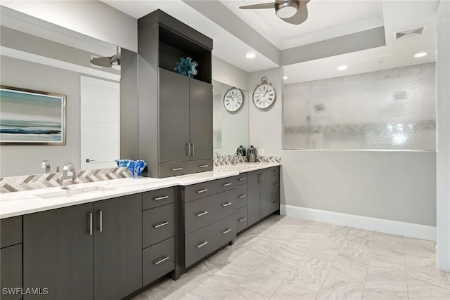 bathroom with vanity, ceiling fan, and a tray ceiling