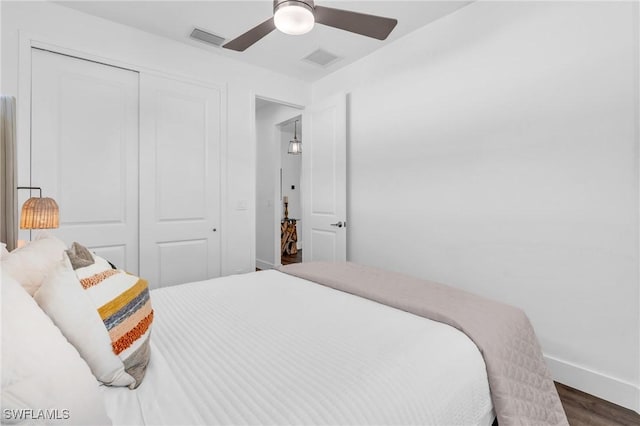 bedroom with dark wood-type flooring, a closet, and ceiling fan