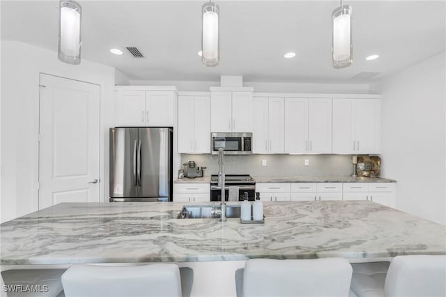 kitchen with a large island, white cabinetry, stainless steel appliances, and decorative light fixtures