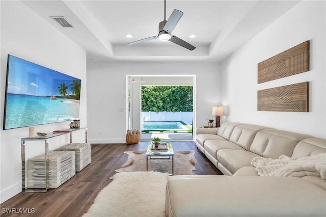 living room featuring ceiling fan, dark hardwood / wood-style flooring, and a raised ceiling