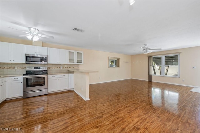 kitchen with white cabinetry, appliances with stainless steel finishes, and hardwood / wood-style flooring