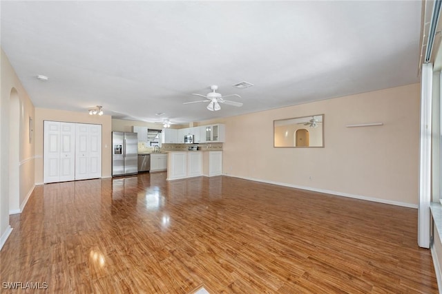 unfurnished living room with hardwood / wood-style flooring, ceiling fan, and sink