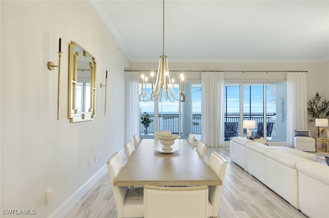 dining room with a notable chandelier, crown molding, and light wood-type flooring