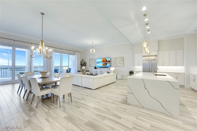 dining room with light hardwood / wood-style floors, ornamental molding, a chandelier, and sink