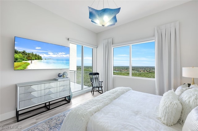 bedroom with hardwood / wood-style flooring, lofted ceiling, multiple windows, and access to outside