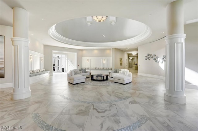 living room featuring a towering ceiling, decorative columns, and a raised ceiling