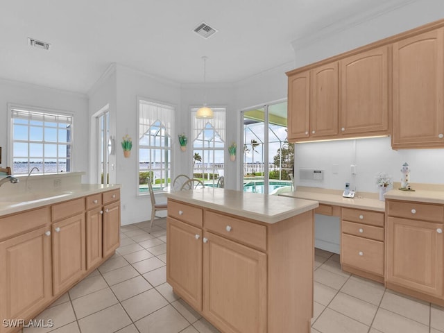 kitchen with light brown cabinetry, sink, crown molding, decorative light fixtures, and a center island