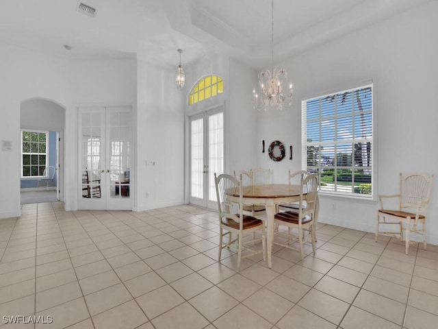 dining area with a high ceiling, light tile patterned floors, an inviting chandelier, and french doors