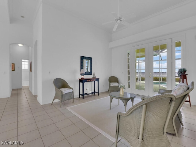 living area featuring a high ceiling, light tile patterned floors, ceiling fan, a water view, and french doors