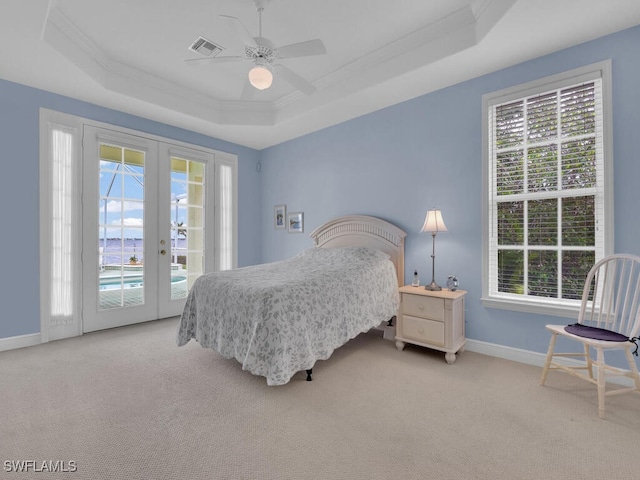 bedroom with a raised ceiling, light carpet, access to exterior, and french doors