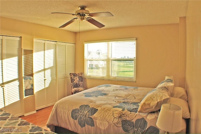 bedroom with ceiling fan, a textured ceiling, and wood finished floors