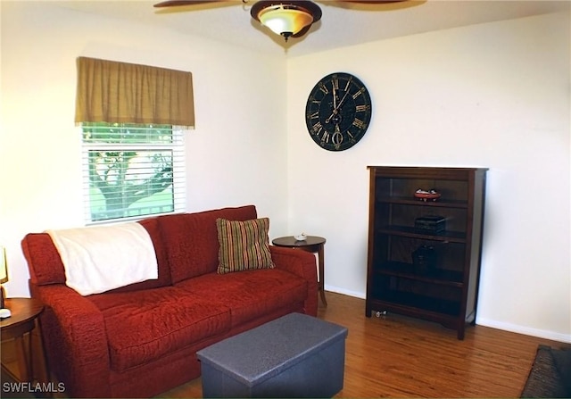 living room featuring wood finished floors, a ceiling fan, and baseboards