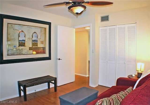 interior space featuring a ceiling fan, visible vents, baseboards, and wood finished floors