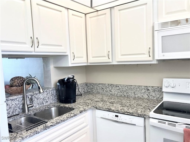 kitchen with light stone counters, white appliances, white cabinets, and a sink