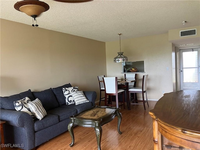 living area featuring a textured ceiling, visible vents, and wood finished floors