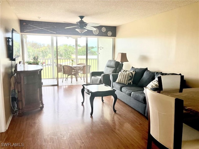 living room featuring a textured ceiling, ceiling fan, and wood finished floors