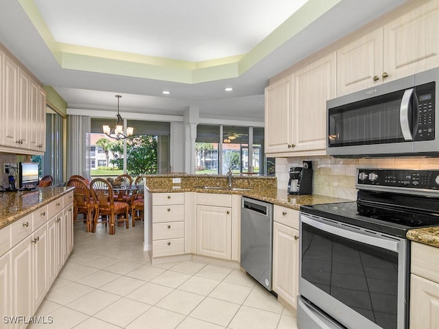 kitchen featuring stainless steel appliances, a raised ceiling, sink, and stone counters