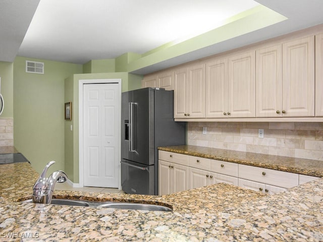 kitchen featuring light stone countertops, sink, high quality fridge, and backsplash