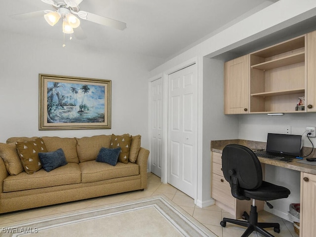 office space with ceiling fan, built in desk, and light tile patterned floors