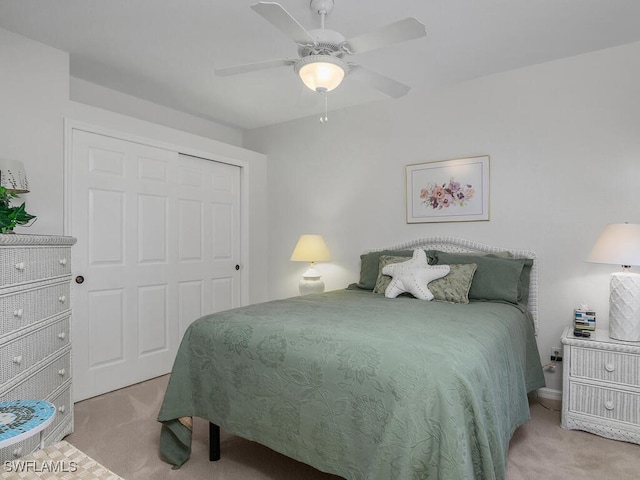 bedroom featuring light colored carpet, a closet, and ceiling fan