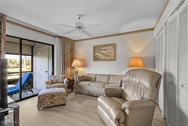 living room featuring ceiling fan, ornamental molding, and light wood-type flooring