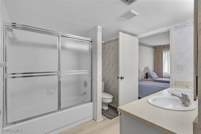 full bathroom with toilet, wood-type flooring, shower / bath combination with glass door, and vanity