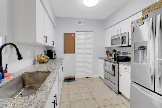 kitchen featuring stainless steel appliances, white cabinetry, light stone countertops, and sink