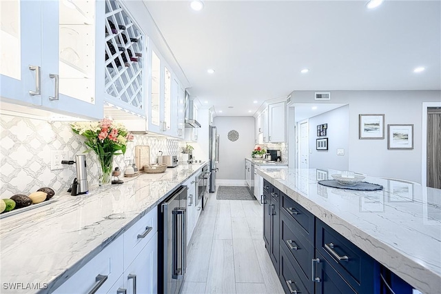 kitchen featuring stainless steel fridge, light stone counters, tasteful backsplash, white cabinets, and beverage cooler