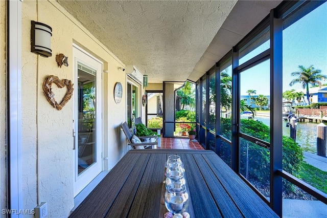 sunroom featuring a water view