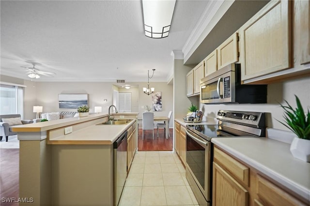 kitchen with appliances with stainless steel finishes, pendant lighting, sink, crown molding, and a center island with sink